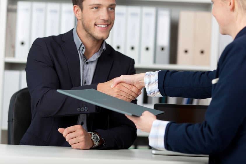 Happy businessman shaking hands with a female interviewer in office.jpeg