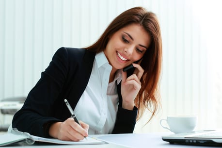 Young happy businesswoman talking on the phone and writing notes in office-1